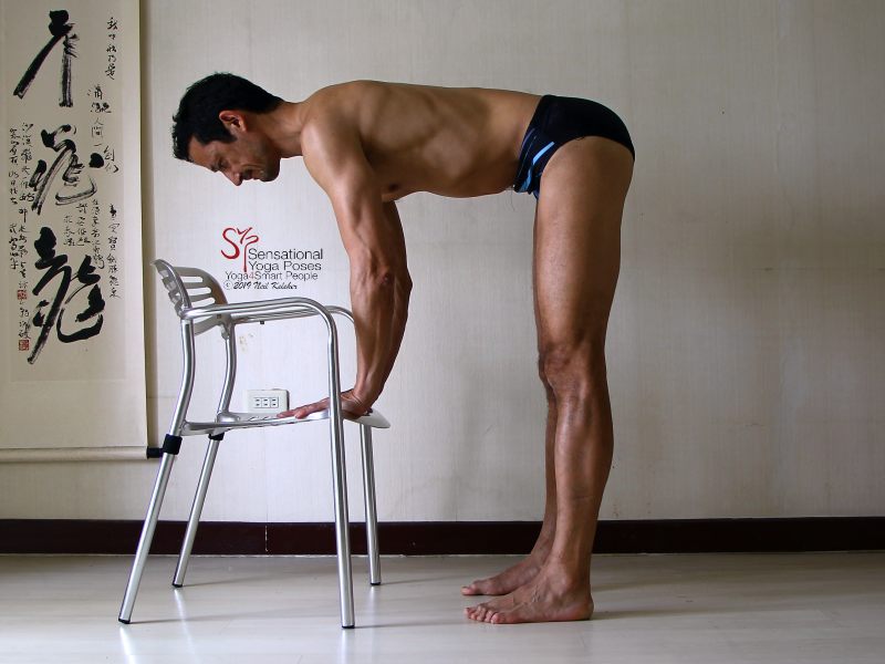 Standing hamstring stretch with hands on a chair and arms engaged to support the weight of upper body. Standing hamstring stretch with hands on a chair and arms engaged to support the weight of upper body. Hamstrings are relaxed with knees straight. Neil Keleher, Sensational Yoga Poses.