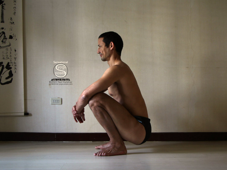 squatting to stretch the quads with heels down Neil Keleher, Sensational Yoga Poses.